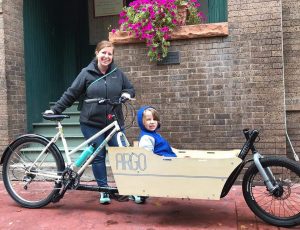 mom taking kid around town in a cargo bike