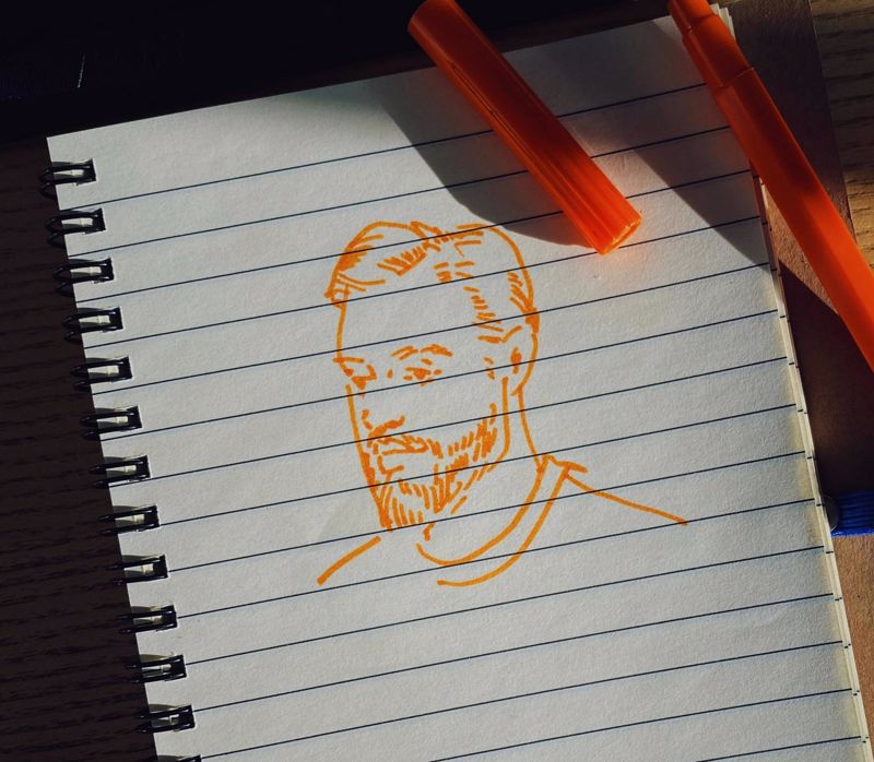 lined notebook paper with a drawing of a bearded man done in orange pen